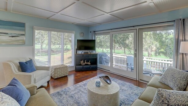 A spacious living room with a large TV, comfortable seating, and a view of the outdoors.