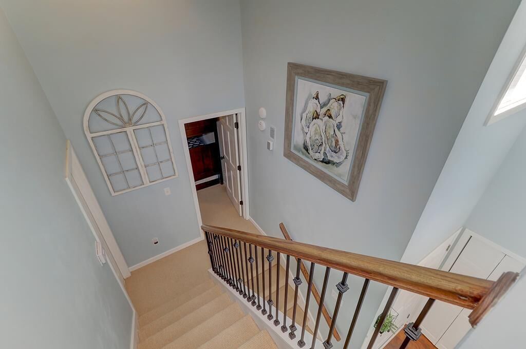 A staircase with a wooden handrail and beige carpet.