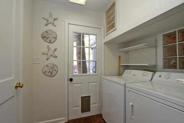 A laundry room with a white door, a window, and a wall-mounted drying rack.