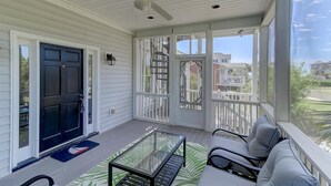 A covered porch with a ceiling fan, a glass table, and a seating area with cushions. - 8 44th Avenue (Isle of Palms)