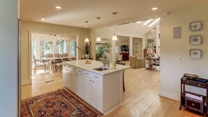 A spacious kitchen with a central island, pendant lighting, and a dining area with chairs and a table. - 8 Hidden Green (Isle of Palms)