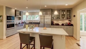 A modern kitchen with a central island, stainless steel appliances, and pendant lighting. - 8 Hidden Green (Isle of Palms)