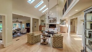 A spacious living area with a high ceiling, skylights, a chandelier, and a large window. - 8 Hidden Green (Isle of Palms)