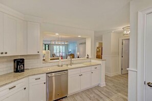 A modern kitchen with white cabinetry, a double sink, and a dishwasher. - 111 Summerhouse Villa (Isle of Palms)
