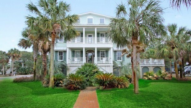 A large, two-story building with a central entrance, surrounded by a well-maintained lawn and palm trees. - 2 55th Ave (Isle of Palms)