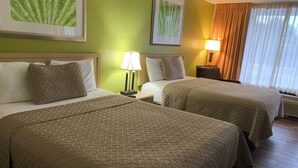 A hotel room with two beds, a nightstand with a lamp, and artwork on the walls. - RW Hotel (Kissimmee)