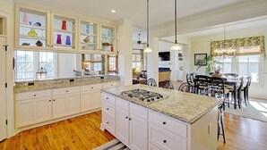 A spacious kitchen with white cabinetry, a granite countertop, and a central island with a stove. - 2603 Palm Boulevard (Isle of Palms)