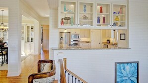 A spacious kitchen with white cabinetry, a central island, and a dining area with a wooden table and chairs. - 2603 Palm Boulevard (Isle of Palms)