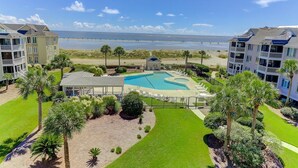 A beachfront hotel with a swimming pool, multiple balconies, and a view of the ocean. - H303 Tidewater (Isle of Palms)