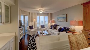 A spacious living room with a large window, white furniture, and a ceiling fan. - H303 Tidewater (Isle of Palms)