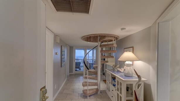 A spiral staircase with a cat tree, a lamp, and a view of the outdoors. - H303 Tidewater (Isle of Palms)