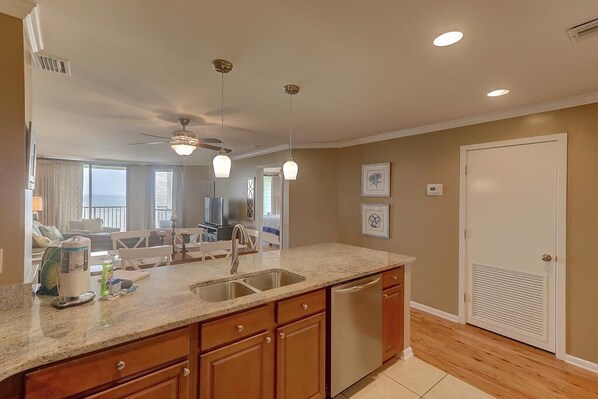 A modern kitchen with granite countertops, a stainless steel dishwasher, and wooden cabinets. - 505 Summerhouse Villa (Isle of Palms)