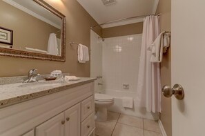 Een badkamer met een wastafel, spiegel, toilet en douche.
