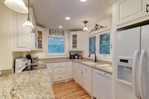 A kitchen with white cabinets, granite countertops, a built-in oven, a sink, and a refrigerator. - 22 Twin Oaks (Isle of Palms)