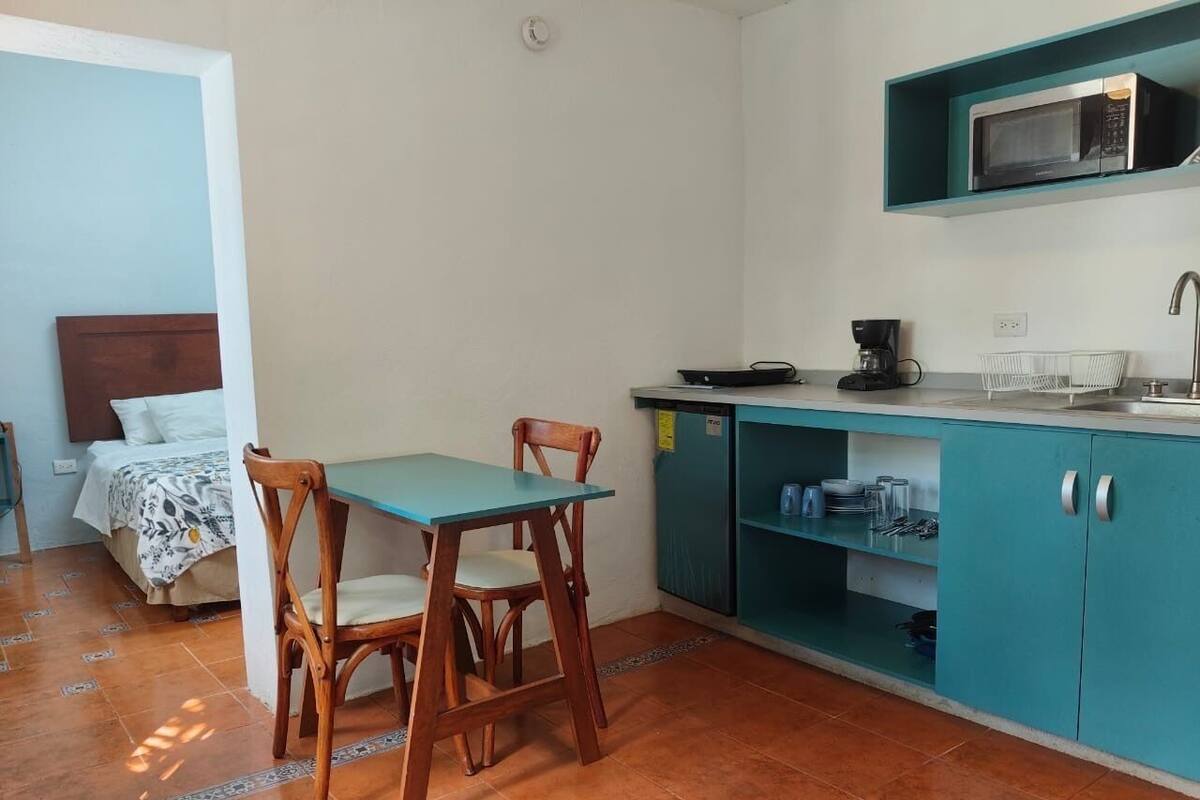 A compact kitchen with teal cabinets, a microwave, and a coffee maker.