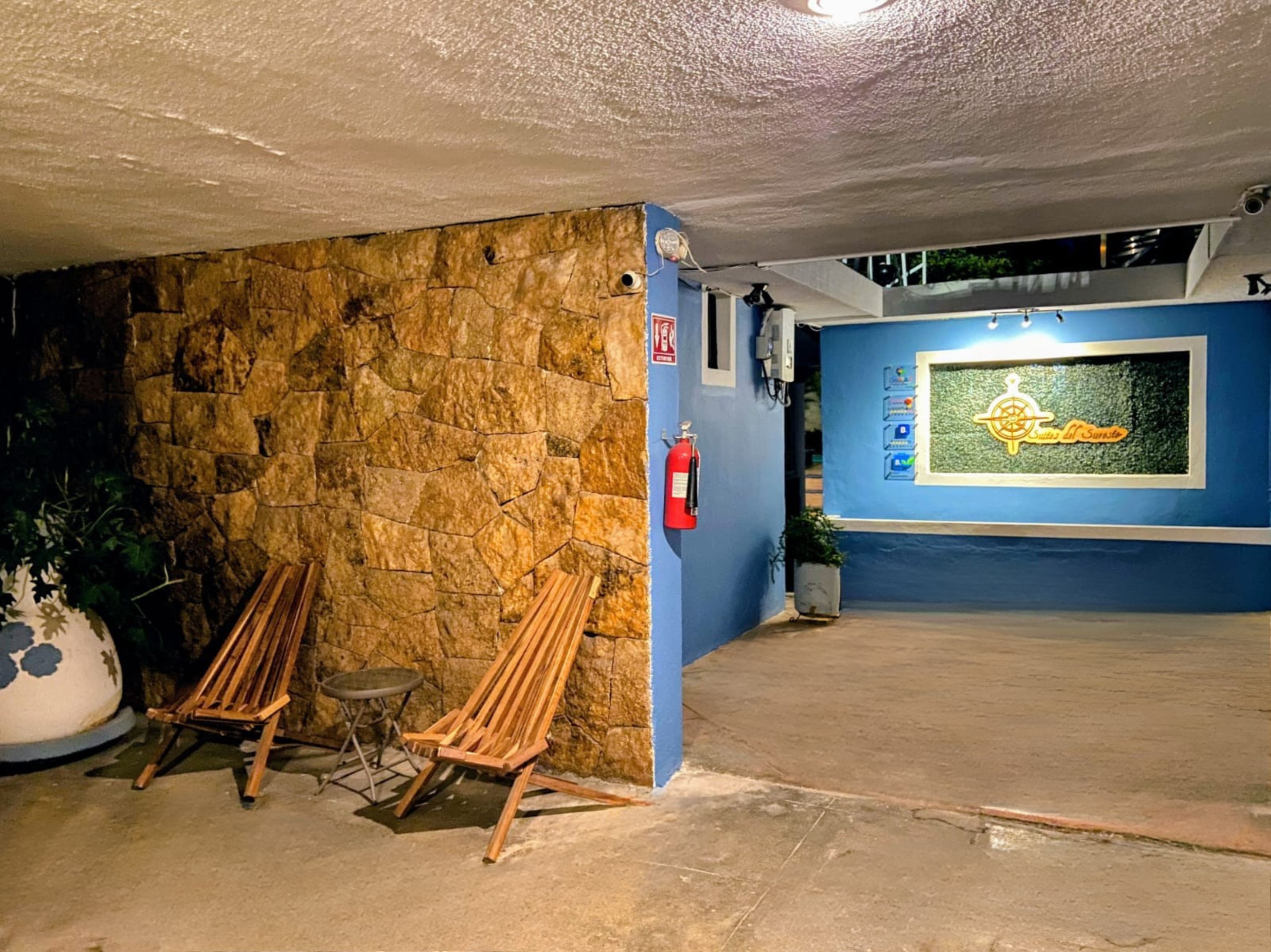 A stone wall with a fire extinguisher, a wooden bench, and a blue wall with a logo.