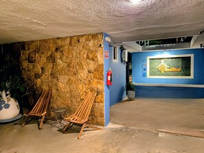 A stone wall with a fire extinguisher, a wooden bench, and a blue wall with a logo. - Suites del Sureste (Mérida)