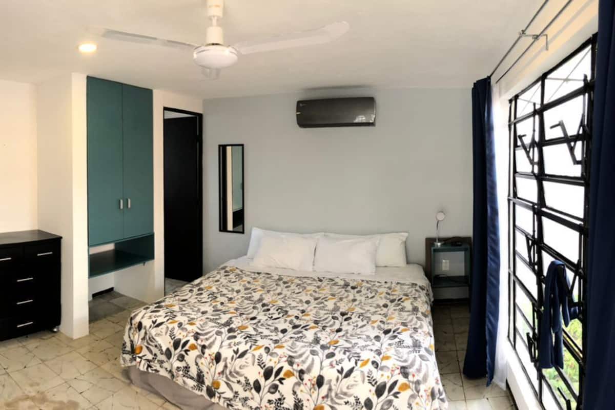 A bedroom with a bed, a desk, a chair, a TV, and a wardrobe.