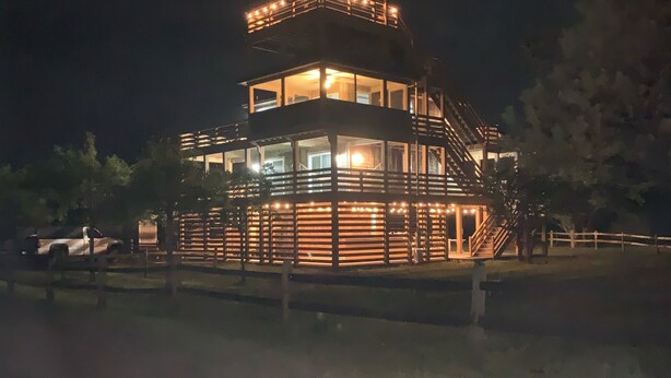 Een gebouw met meerdere verdiepingen, een balkon en een trap, omgeven door een hek.