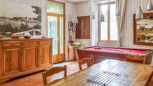 A billiards table with a red felt surface, wooden cabinets, and a dining table with chairs. - Le Patio by Interhome (Saint Malo)