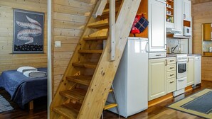 A wooden staircase leading to a kitchen with white cabinets, a microwave, and an oven.