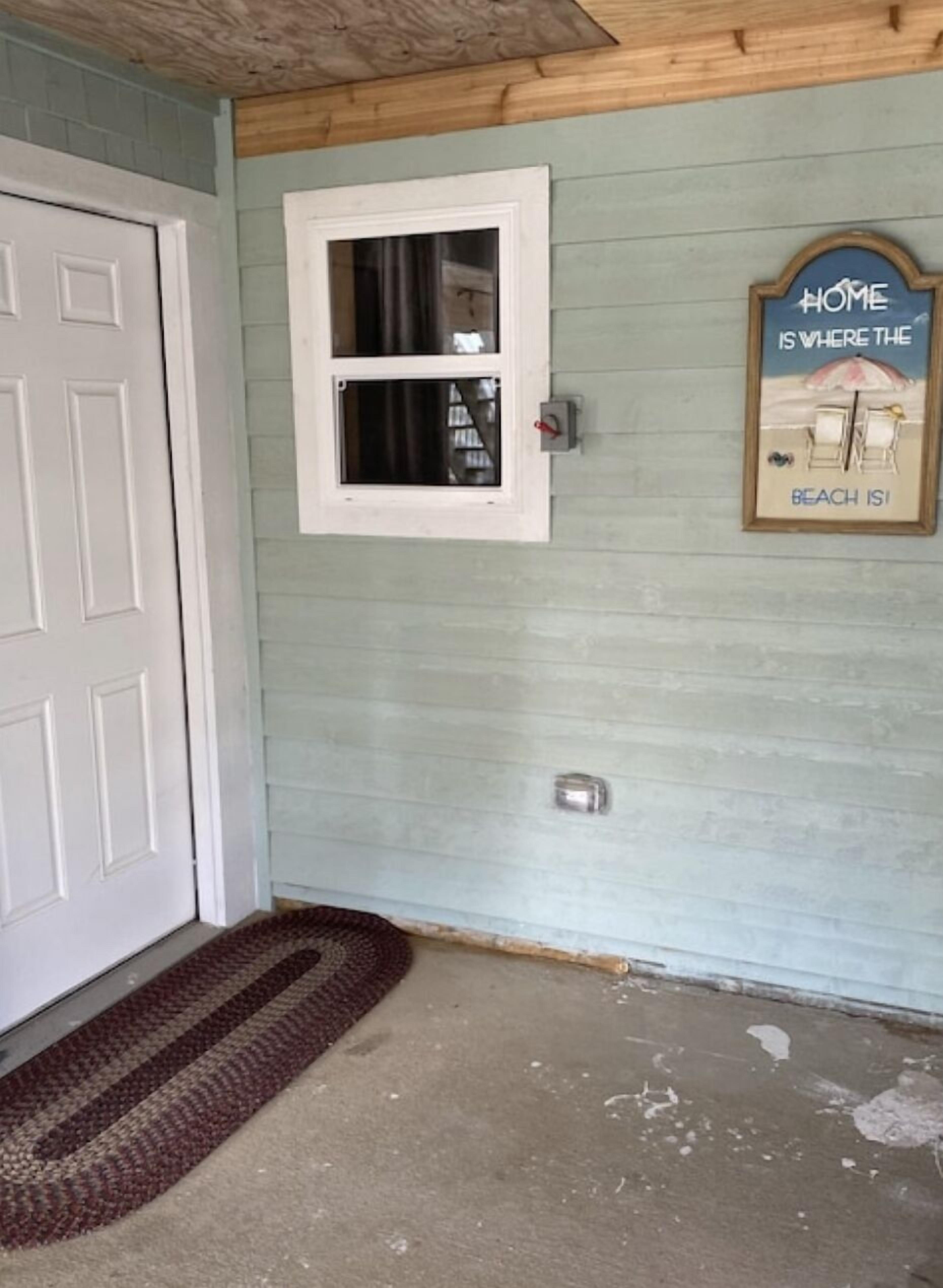 A room with a white door, a small window, and a welcome sign on the wall.