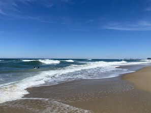 Una playa con olas, un muelle y cielo despejado.