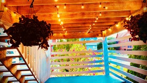 A wooden staircase with a blue bench at the top, leading to a white fence with colorful plants.