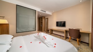 A hotel room with a large bed, a desk, a TV, and a chair. - Bo Yi Hotel (Guangzhou)
