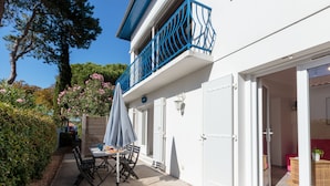 A white building with a blue balcony, a table with chairs, and a covered outdoor area. - Les Mâts by Interhome (Saint Palais sur mer)