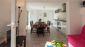 A modern kitchen with white cabinets, a dining area with a red tablecloth, and a bright, open space with natural light. - Les Mâts by Interhome (Saint Palais sur mer)