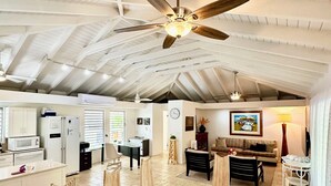 Un salón amplio con techo alto, ventilador de techo y comedor con mesa y sillas.