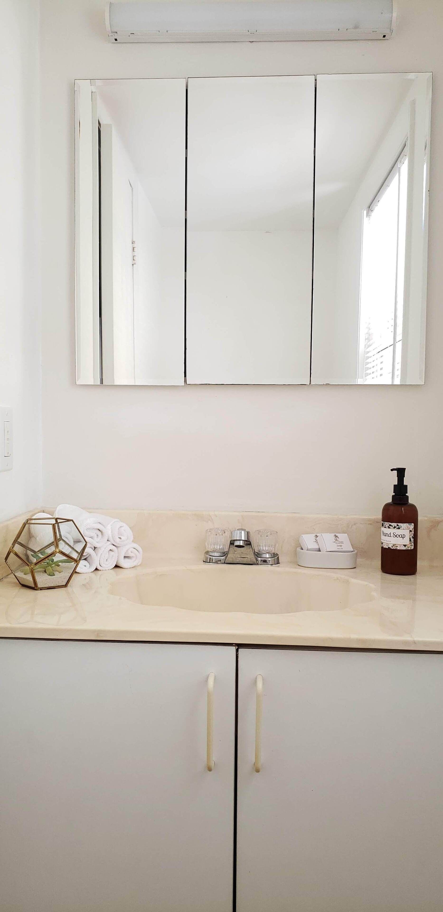 Un bagno con uno specchio grande, un lavandino e un dispenser di sapone.
