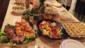 A buffet table with various dishes, including meats, cheeses, and vegetables, set up in a dining area with a fireplace and decorative items in the background. - Filmed in Movie-Large Charming Midtown 4000 f²,5 BR,8 beds,3.5 bath sleeps 14 (Memphis)