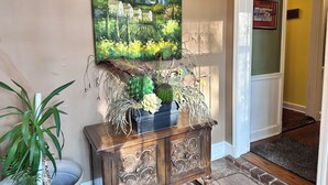 A hallway with a painting of a landscape, a wooden cabinet with decorative carvings, and a potted plant. - Filmed in Movie-Large Charming Midtown 4000 f²,5 BR,8 beds,3.5 bath sleeps 14 (Memphis)