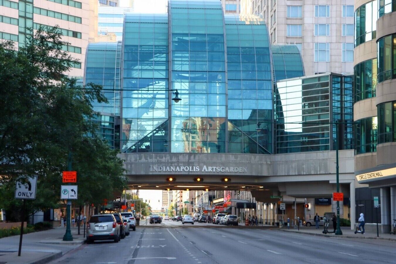 A modern building with a glass facade and a sign for Indianapolis Artsgarden.