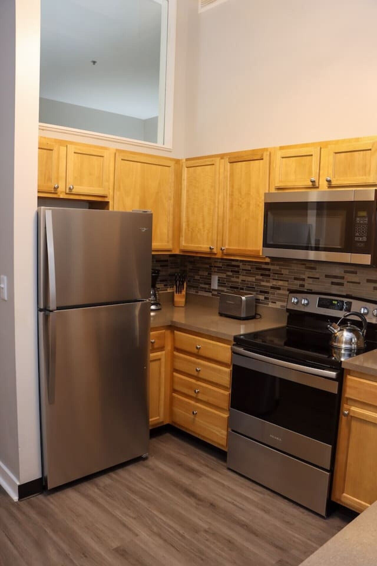 A kitchen with wooden cabinets, stainless steel appliances, and a tiled backsplash.