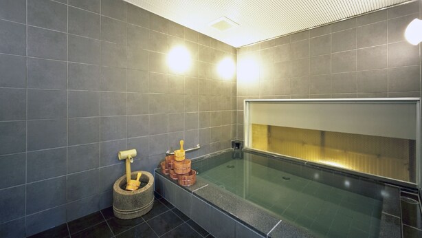 Un baño moderno con bañera de hidromasaje con cerramiento de vidrio, un mortero y maja de piedra, y un perchero para toallas.