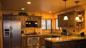 A kitchen with wooden cabinets, stainless steel appliances, granite countertops, and a hanging light fixture. - Cozy and lakefront cabin on Rainbow lake, large fenced deck and 2 grills!!! (Pinetop-Lakeside)