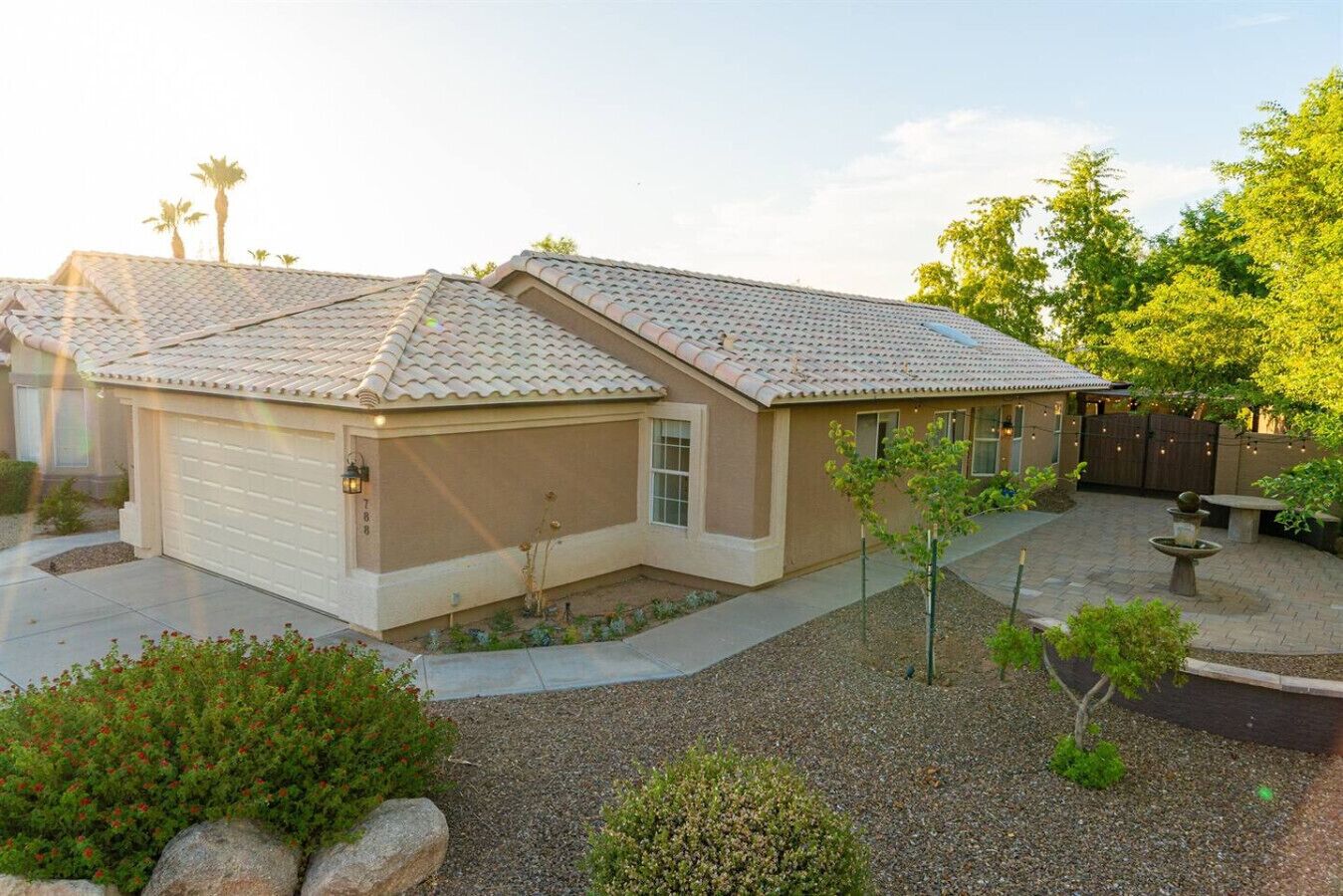 A two-story house with a garage, a patio with a fountain, and a small garden area.