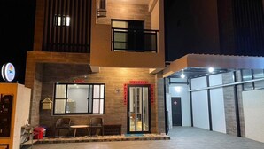 Un edificio moderno con recepción, un comedor con sillas y una entrada con puerta de vidrio.
