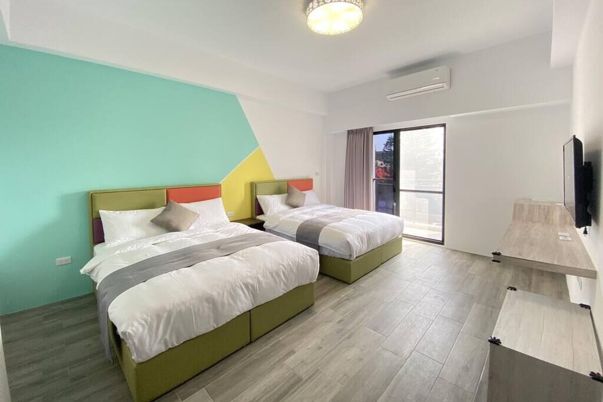 A hotel room with two beds, a large window, and a flat-screen TV.
