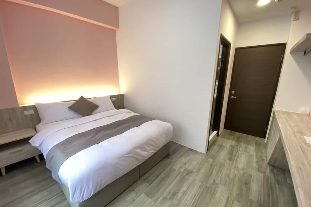 A modern bedroom with a large bed, a bedside table, and a wardrobe.