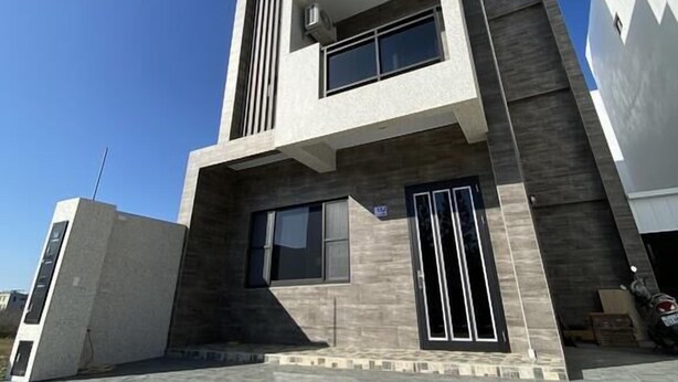 Un edificio moderno de varios pisos con techo plano, amplios ventanales y una zona de entrada con baldosas.