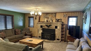 Un salon chaleureux avec une cheminée en pierre, des murs en bois et un lustre.