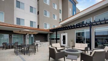 A hotel exterior with outdoor seating, a fire pit, and a stone wall.
