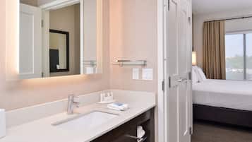 A hotel bathroom with a large mirror, a sink, and a towel rack.