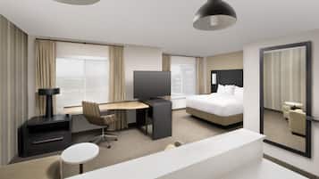 Habitación de hotel con cama, escritorio, televisor, silla, mesita pequeña y un espejo grande.