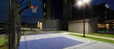 Un campo da basket all'aperto vicino a un edificio con un canestro ben visibile.