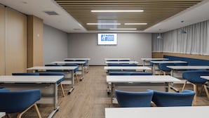 A conference room with tables and chairs, a projector screen, and a sign for Holiday Inn Express. - Holiday Inn Express Pudong Chuansha by IHG (Shanghai)